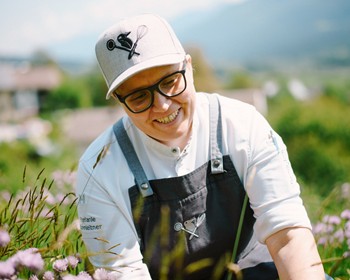 Köchin pflückt Blumen und Kräuter im Garten