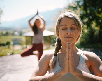 Zwei Frauen machen Yoga auf einer Terrasse