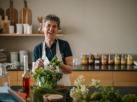 Mitarbeiterin vom Daberer in der Workshop-Küche mit Kräutern in der Hand