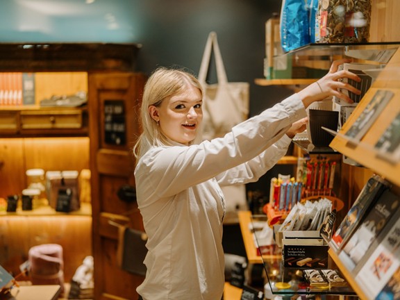 Mitarbeiterin im Hotel Daberer füllt Regale im Shop auf