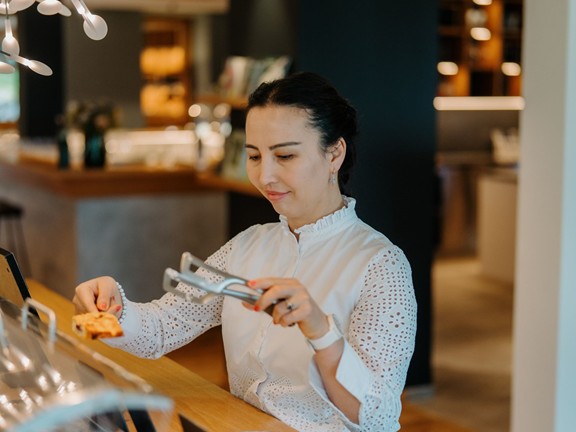 Restaurantmitarbeiterin holt einen Kuchen aus der Theke